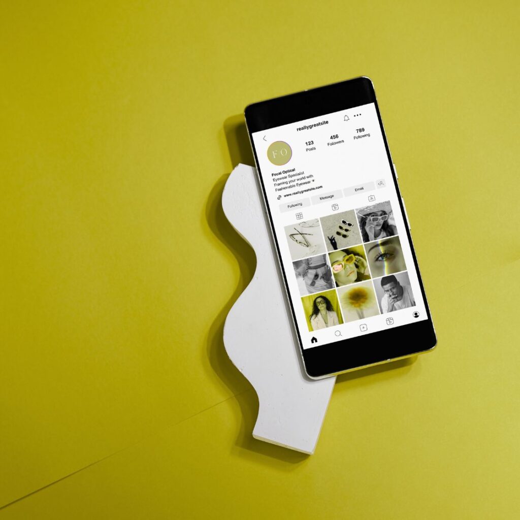 Un smartphone affichant un profil Instagram sur un fond jaune, illustrant l’importance d’une identité visuelle harmonieuse et professionnelle sur les réseaux sociaux.